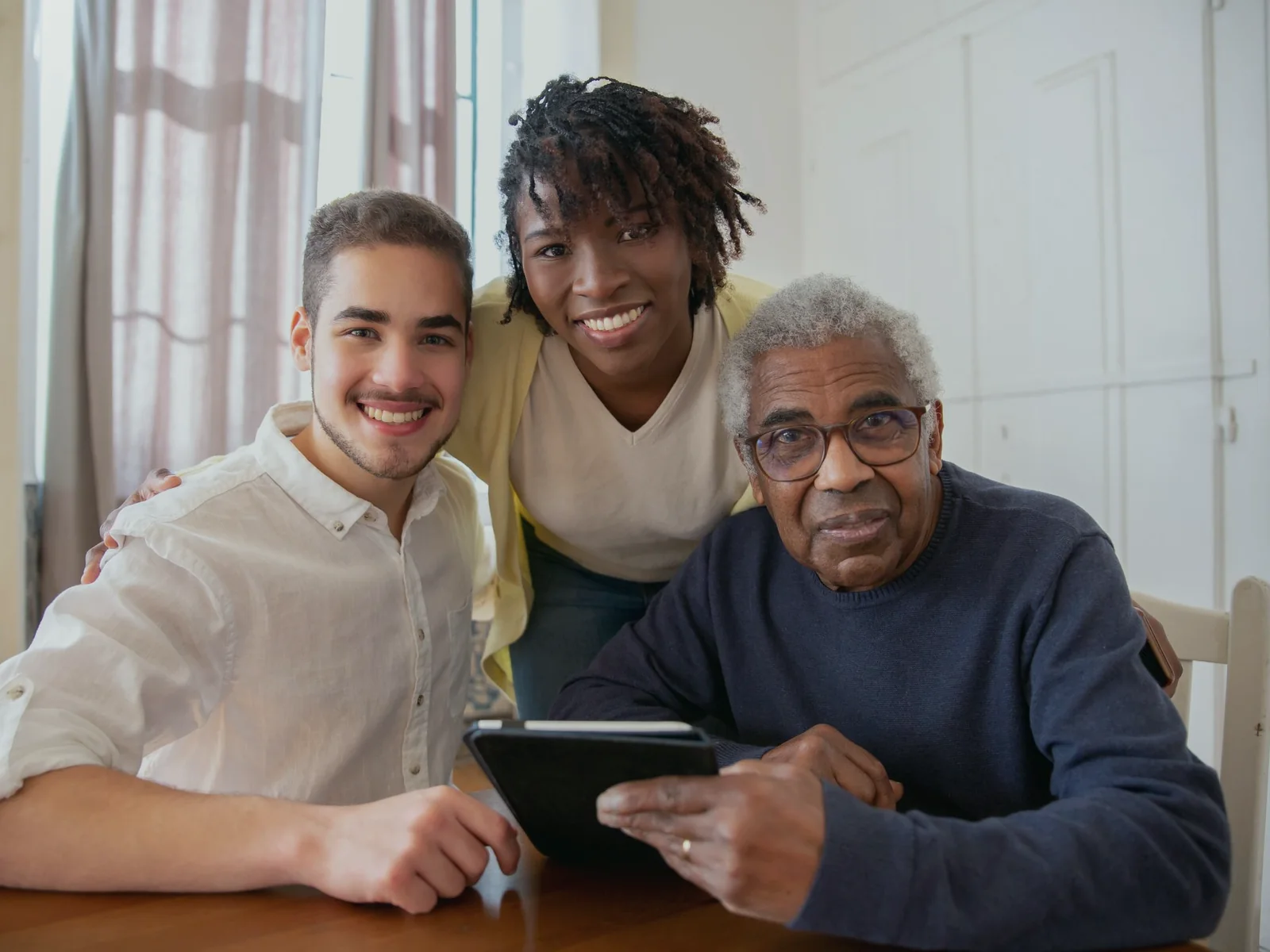 Older adult and two people reviewing information together on a tablet