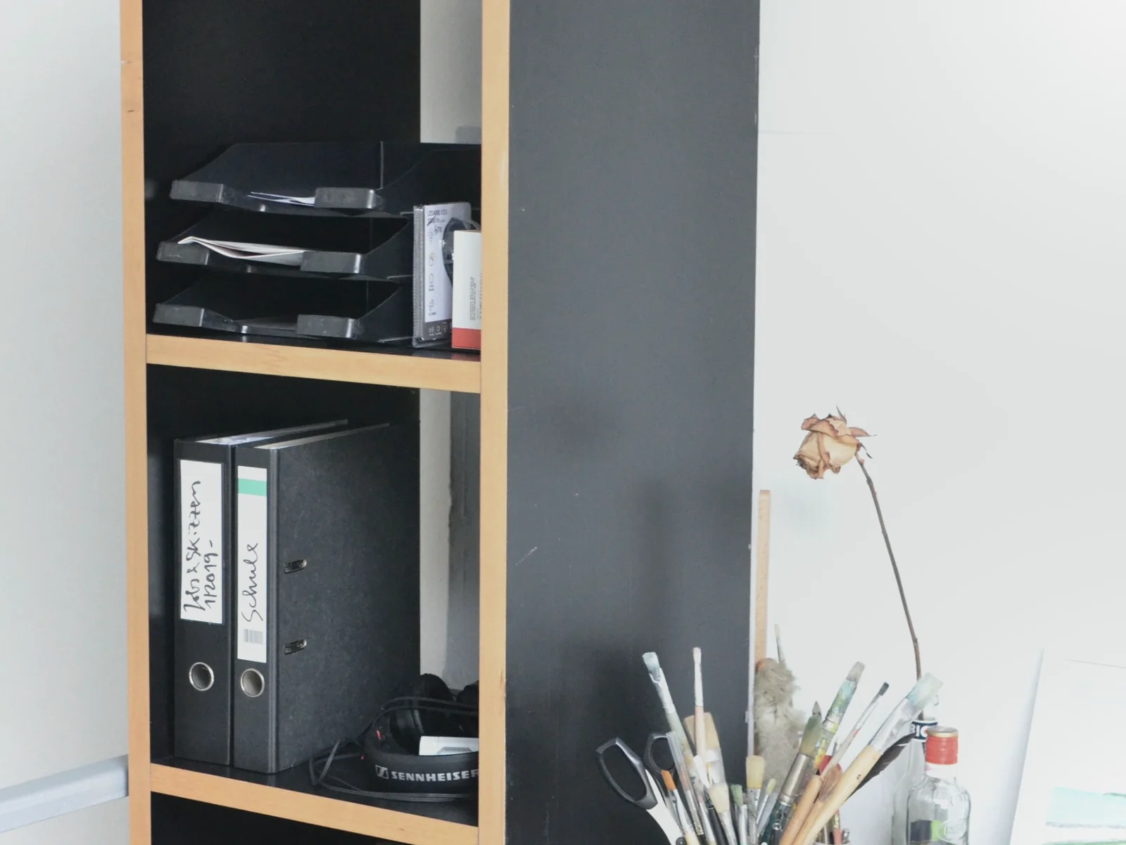 Labeled binders and document trays arranged on a shelf