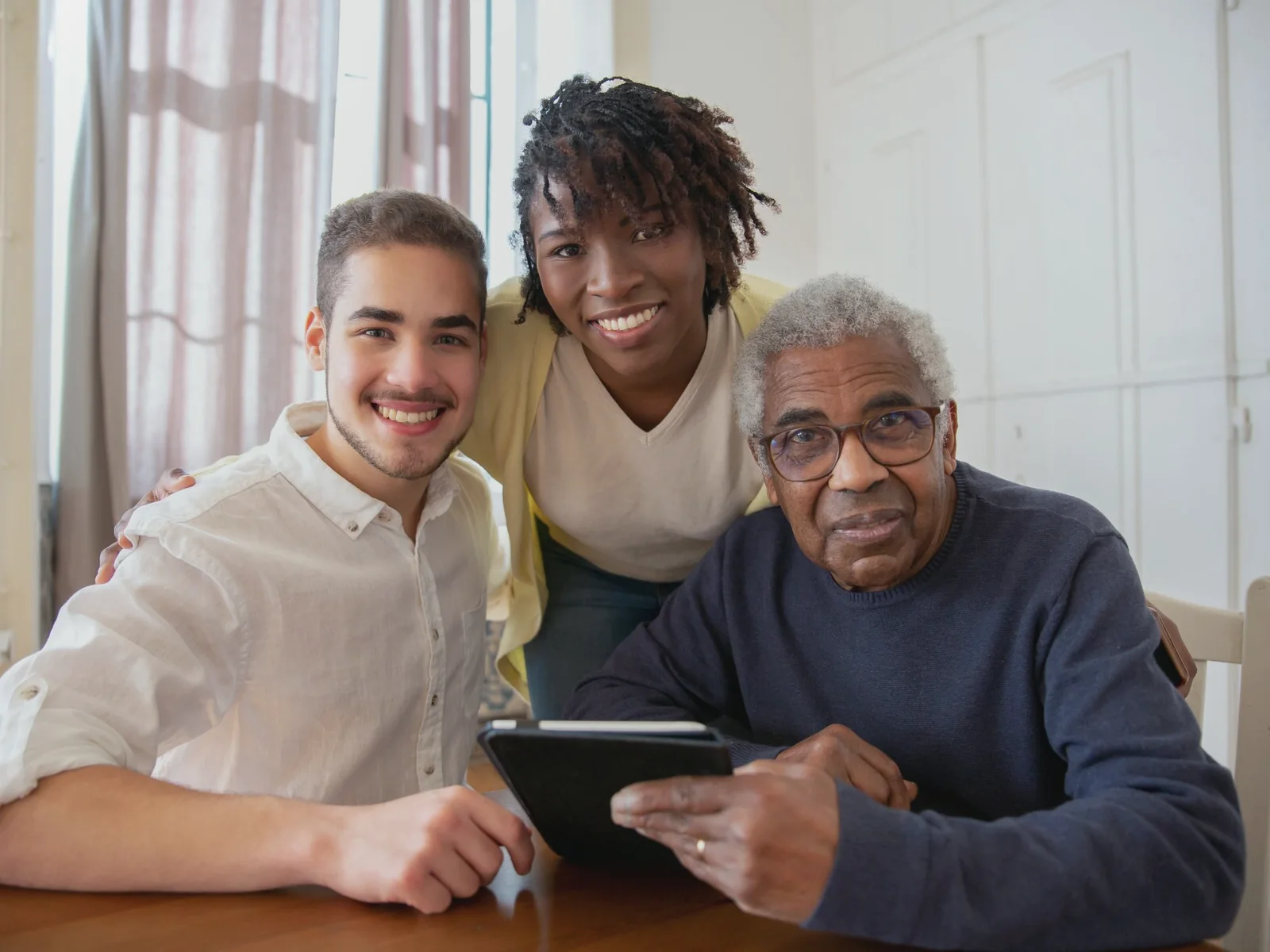 Three family members gathered around a tablet at home