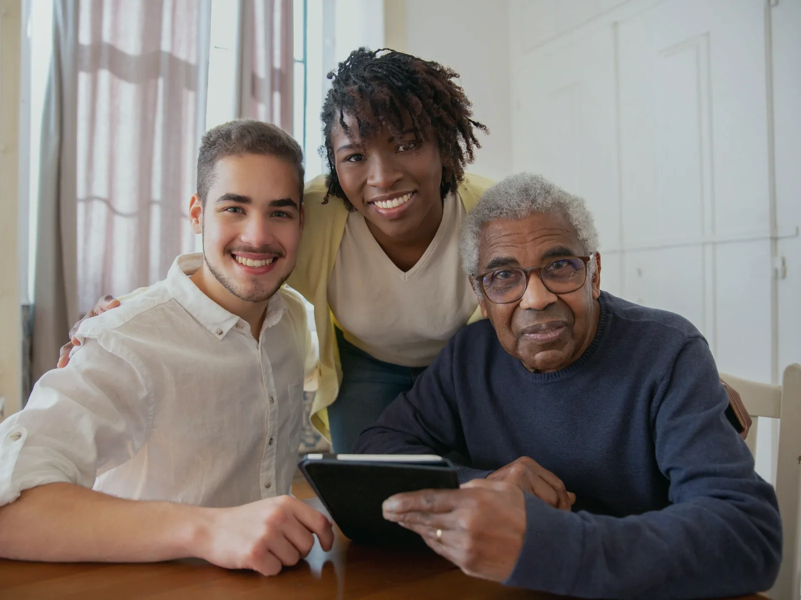 Older adult and two family members looking at a tablet together