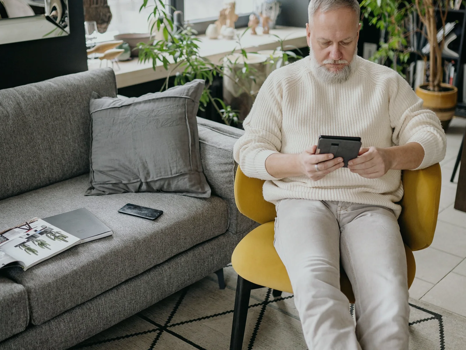 Older adult using a tablet in a bright living room