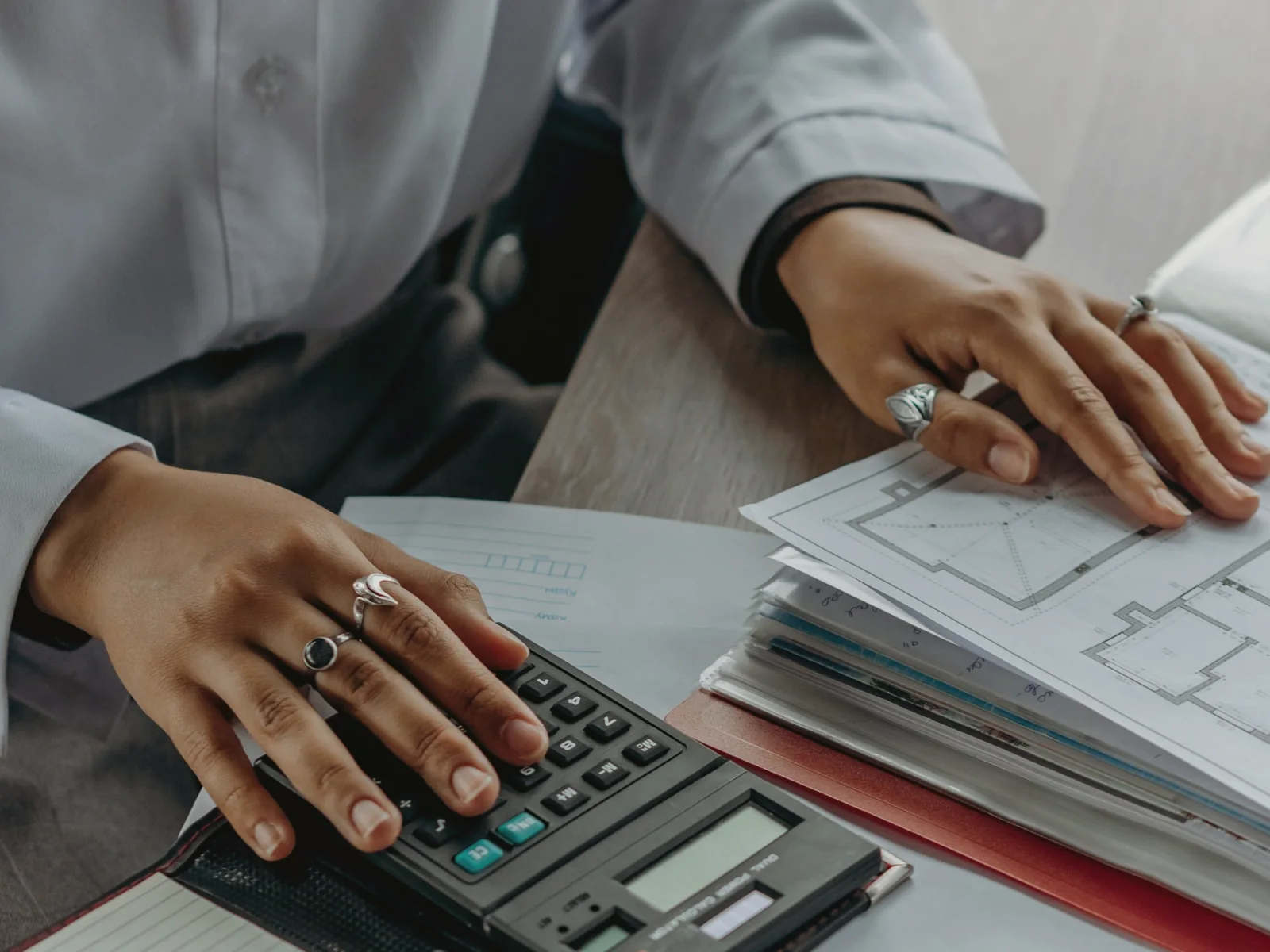 Hands checking paperwork and an inventory beside a calculator